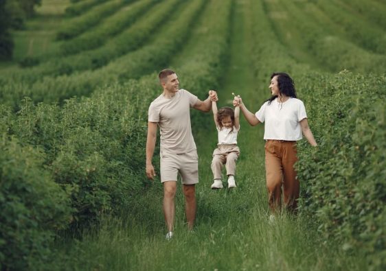 A happy family walking in a lush, green rural field together.
